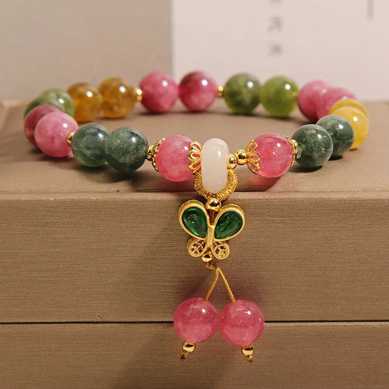 Colourful tourmaline butterfly pendant bracelet with rhinestone details on a woman's wrist.