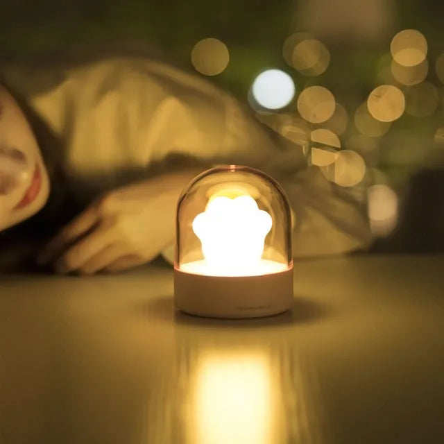Grey cat paw shaped night light with USB charging port and control button showing soft illumination