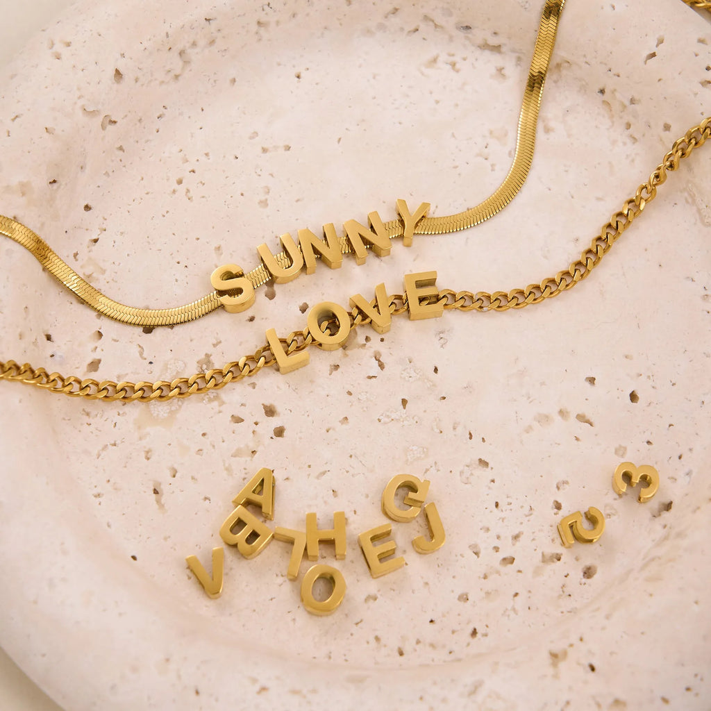 Titanium steel necklace with 40.5cm chain and electroplated gold charms showing numbers and letters for personalisation