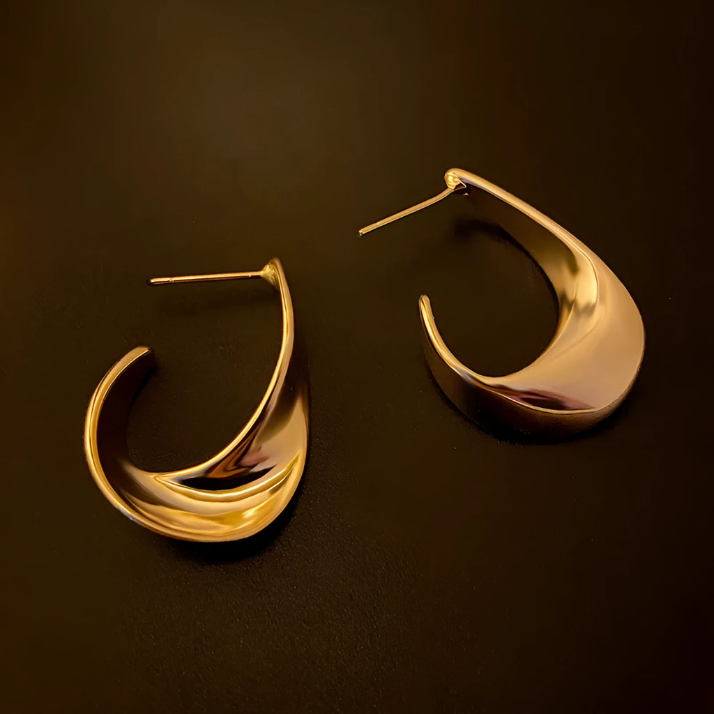 A pair of twisted geometric design metal earrings in gold or silver electroplated finish.