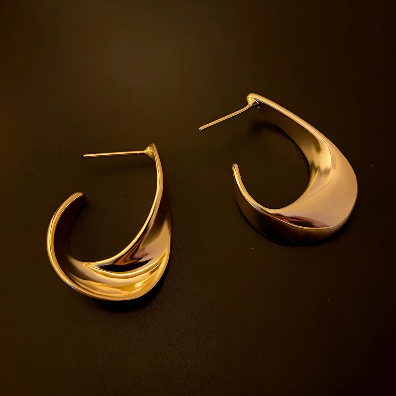 A pair of twisted geometric design metal earrings in gold or silver electroplated finish.