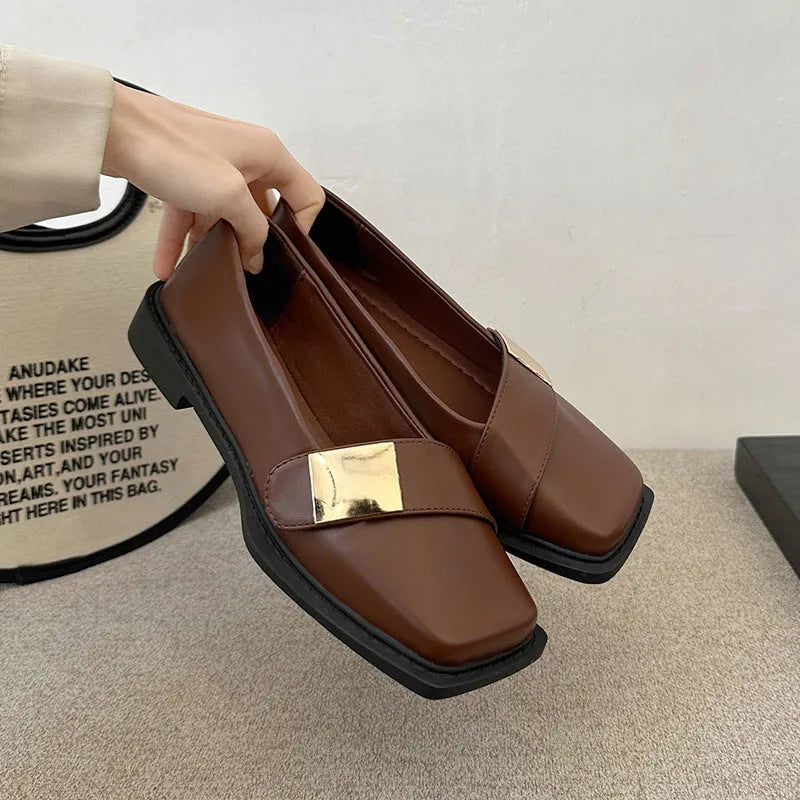 Women's beige square toe flat heel loafers with a silver metal buckle on the upper.