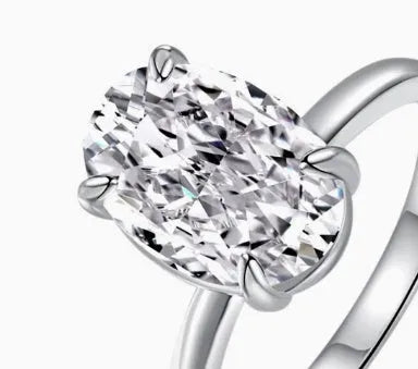 Oval women's ring in 9 silver with four-claw setting holding a 6x9mm gemstone, shown in gold and silver finishes.