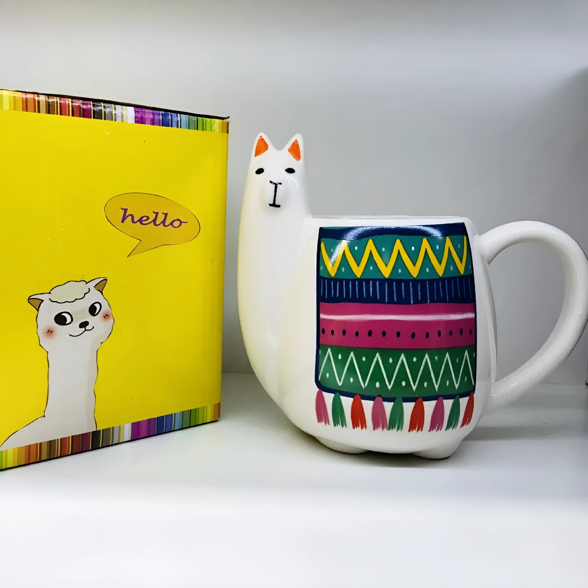 Colourful cartoon alpaca design on a white ceramic mug with a handle.
