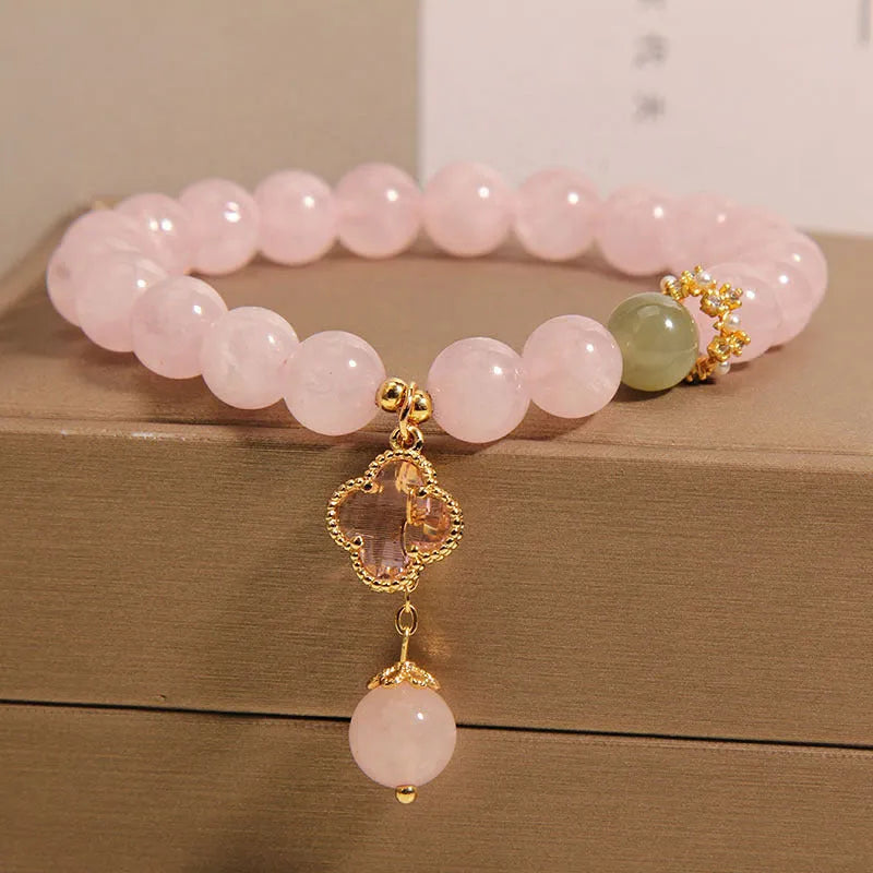 Pink crystal bracelet with four-leaf clover pendant and rhinestone details