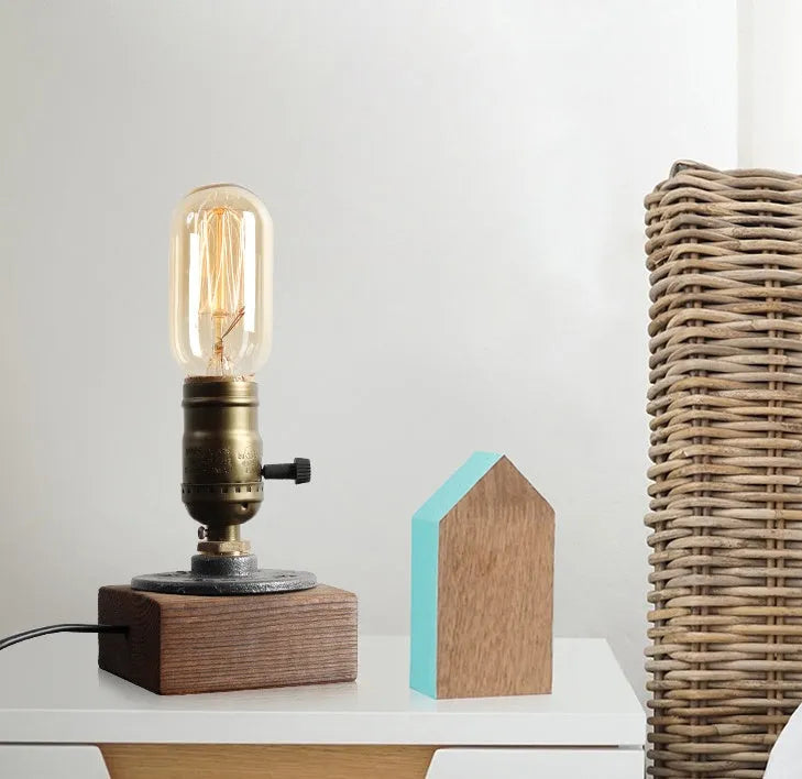 Water pipe table lamp with wood and iron construction, 9 cm wide and 13 cm tall, on a bedside table