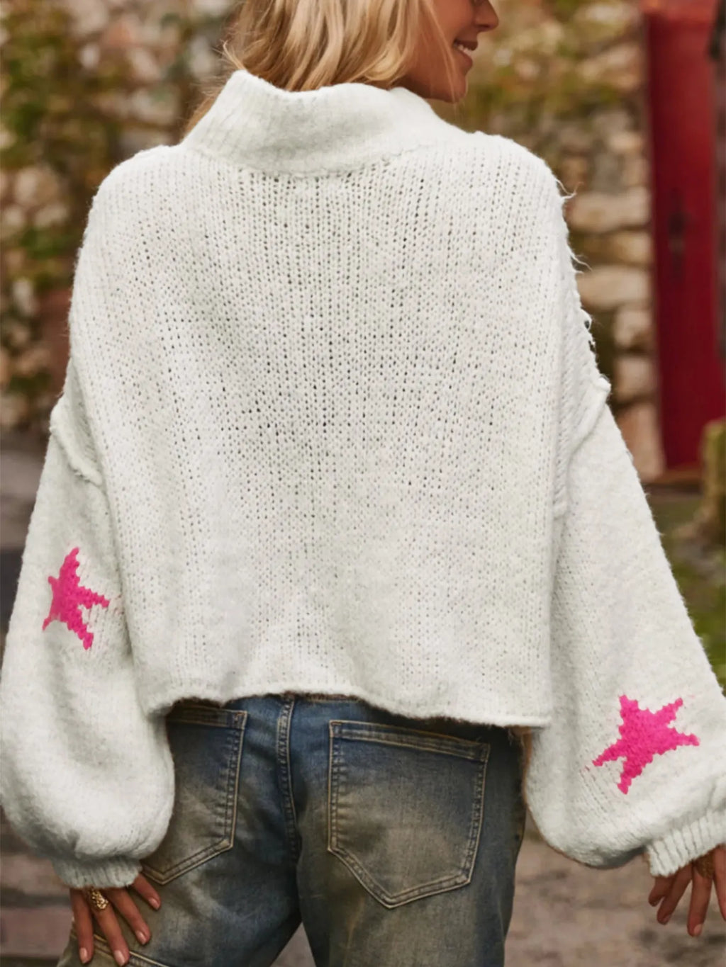 White women's turtleneck pullover sweater with a black five-pointed star pattern on the front.