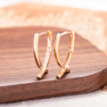 Pair of rose gold cross-shaped earrings on a plain background, showing pierced post design.