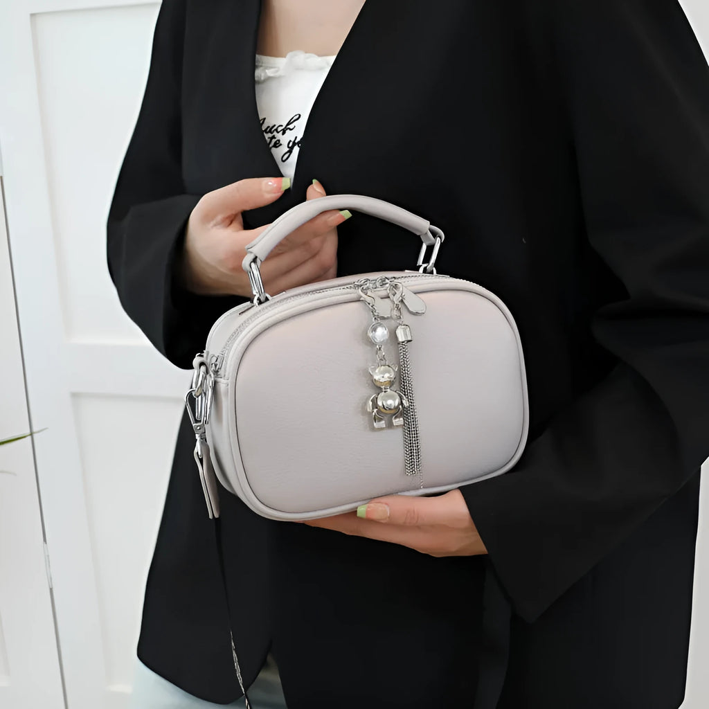 Oval-shaped women's small square bag in PU with double shoulder strap and internal phone pocket.
