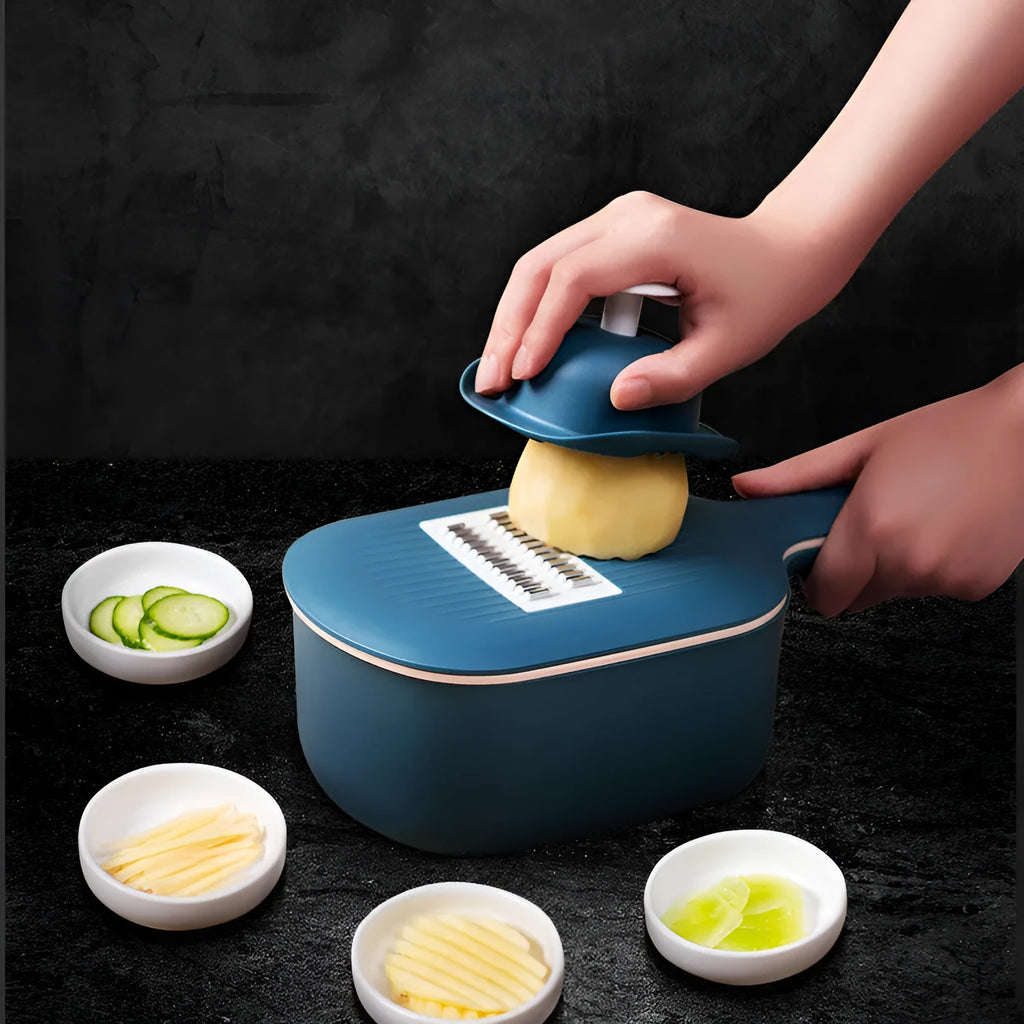 Dark blue vegetable cutter kitchen tool with hand guard, four stainless steel blades, and a white drain basket.
