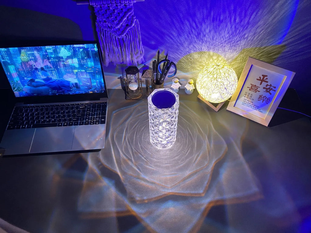 Clear acrylic rose-shaped LED table lamp with touch controls on a wooden surface.