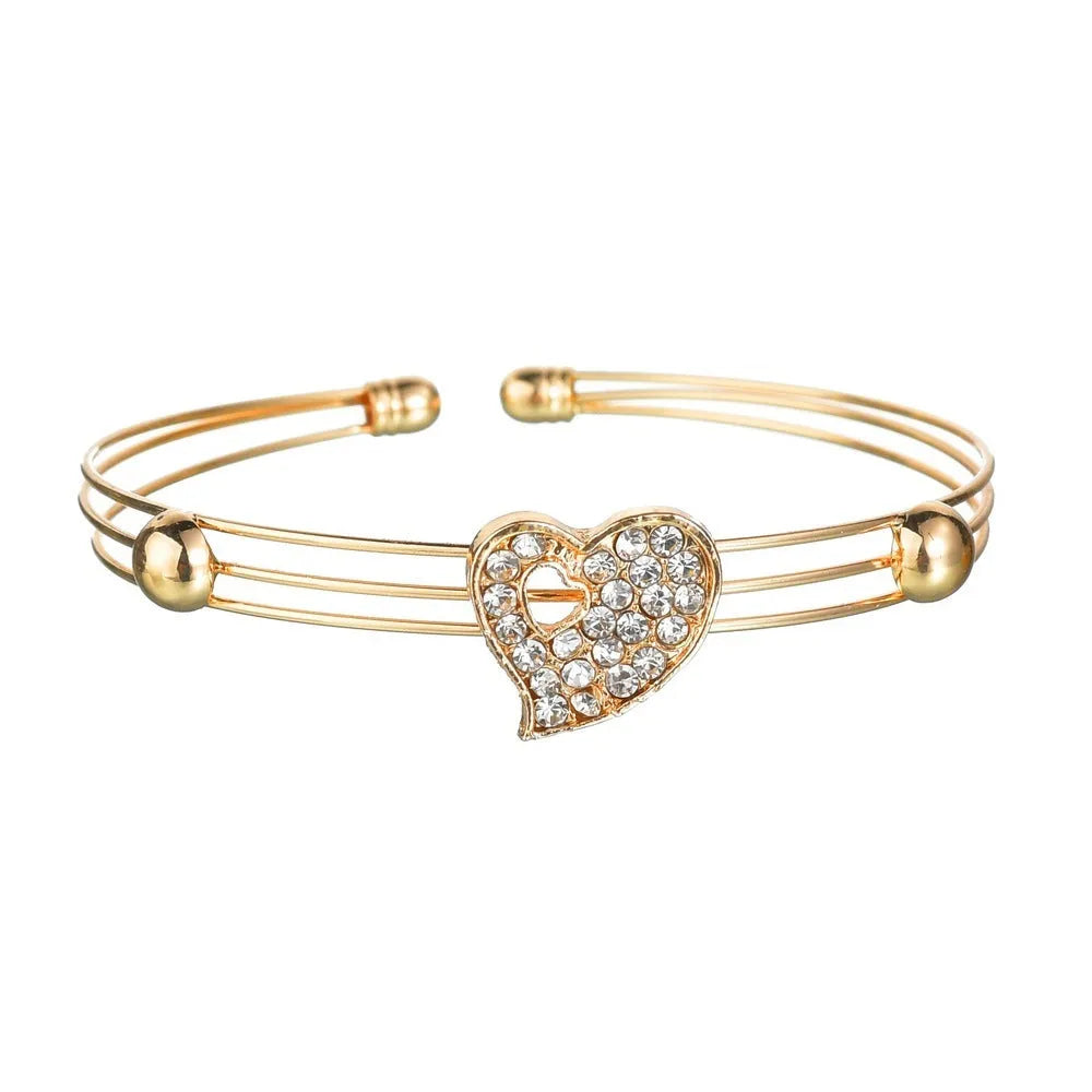 Gold electroplated alloy women's jewellery set with love, water drop, and bell patterned earrings, pendant, and bracelet.