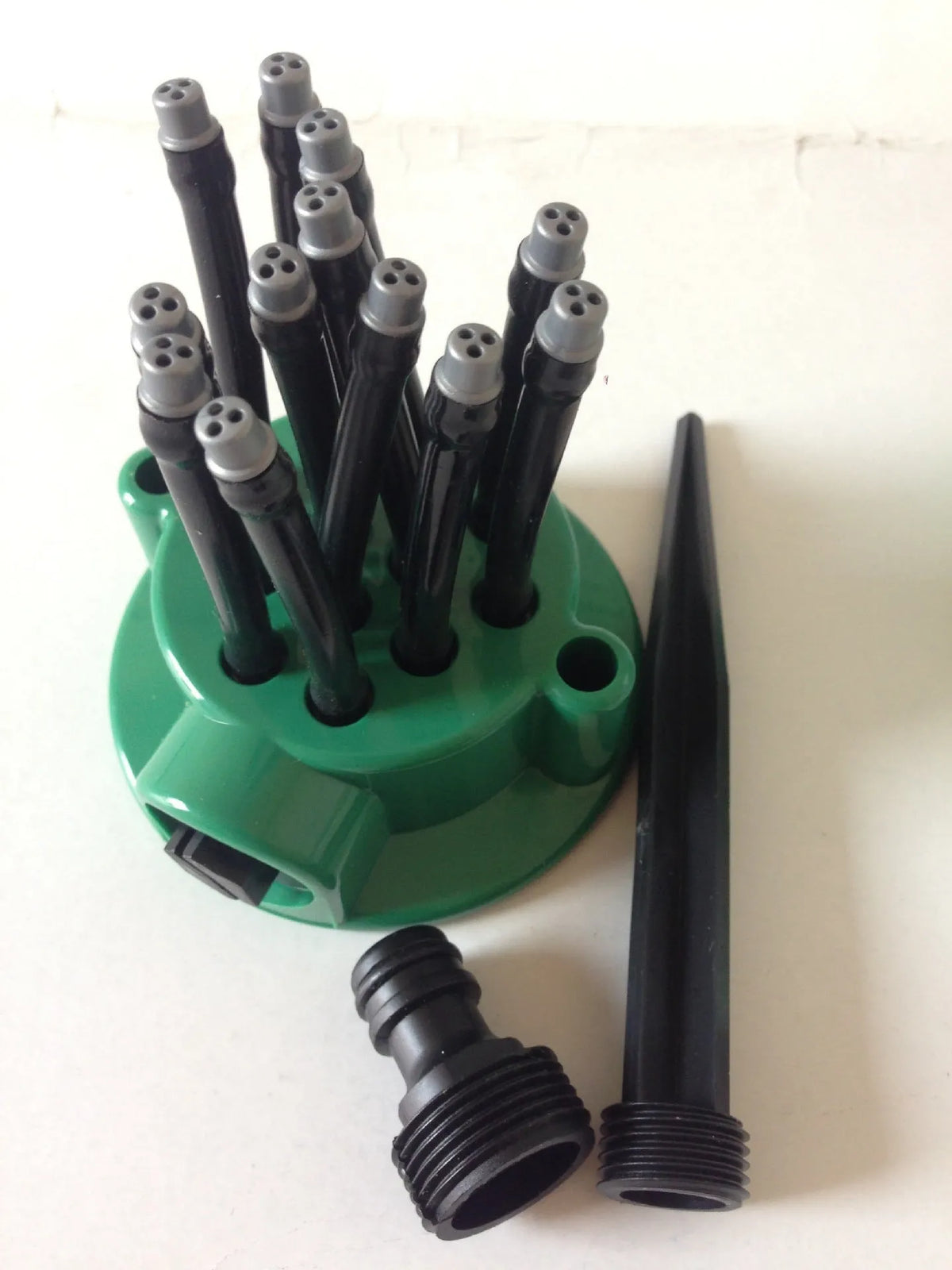 Green plastic adjustable lawn sprinkler with flexible watering noodles on a 9cm base.