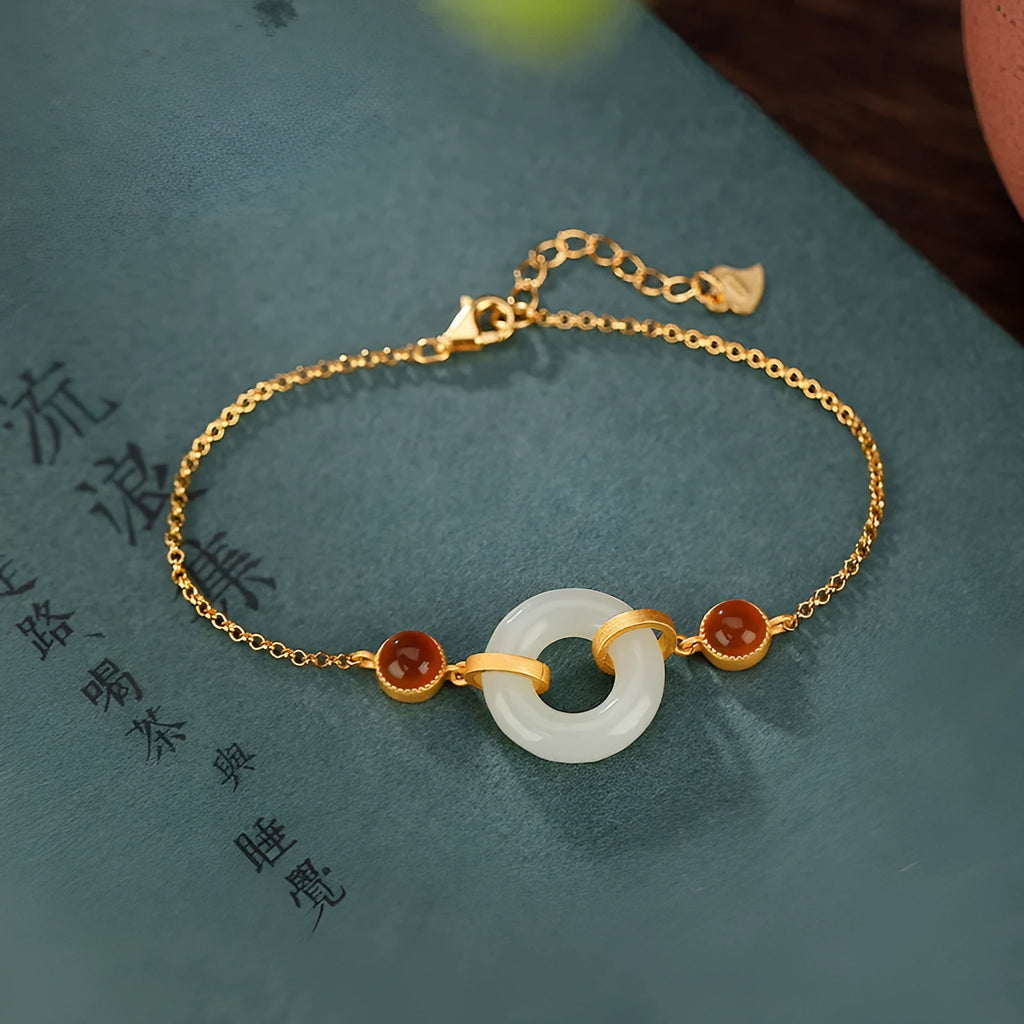 Gold-coloured women's bracelet with a silver base and an inlaid green Hetian jade charm, showing a peace buckle clasp.