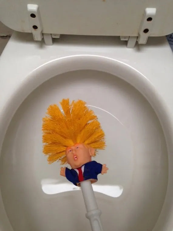 Yellow plastic Trump novelty toilet brush with a hanging slot on the handle.