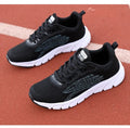 Women's low-cut black and white casual running sneakers with cross-strap detail and a lightweight MD sole.