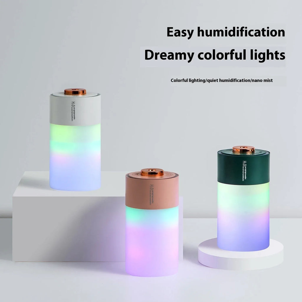 Pink column-shaped USB desk humidifier with colourful LED mist on a wooden surface.