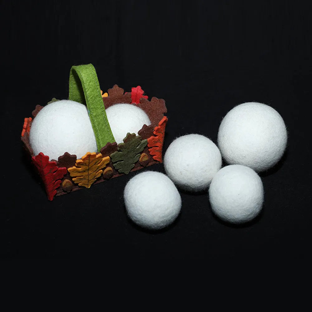 Set of 100% wool anti-static drying balls next to a plain cotton storage bag on a laundry background.