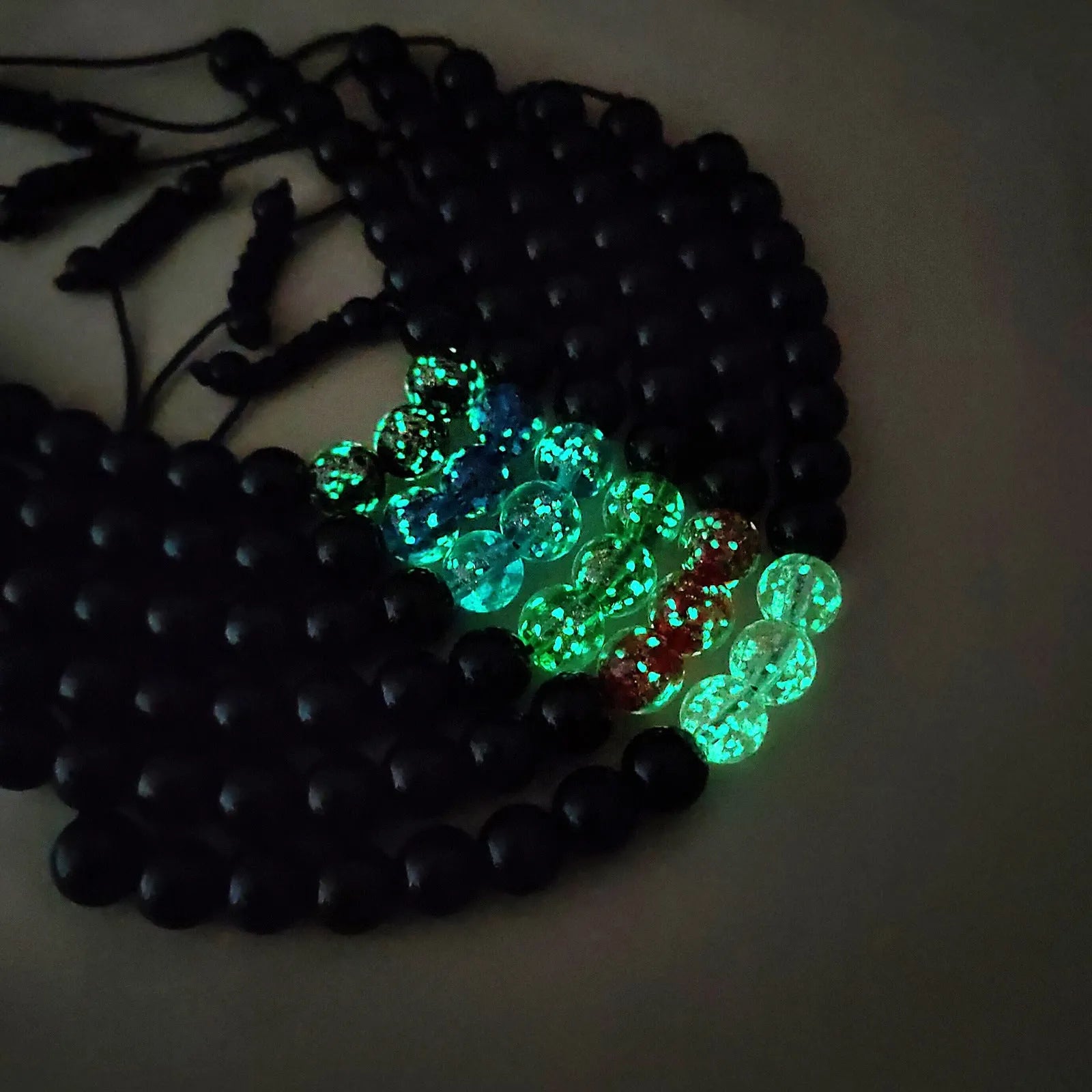 Geometric adjustable bracelet with luminous glass beads in sapphire blue on a wrist.