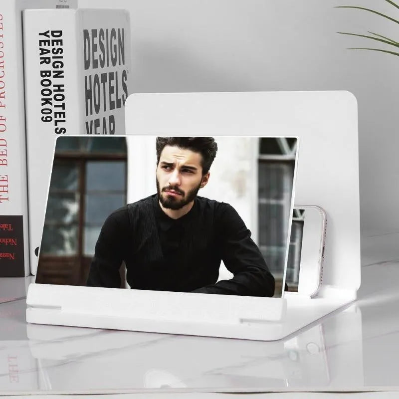 White 9-inch phone screen amplifier with plexiglass lens on a fibreboard base next to a smartphone.