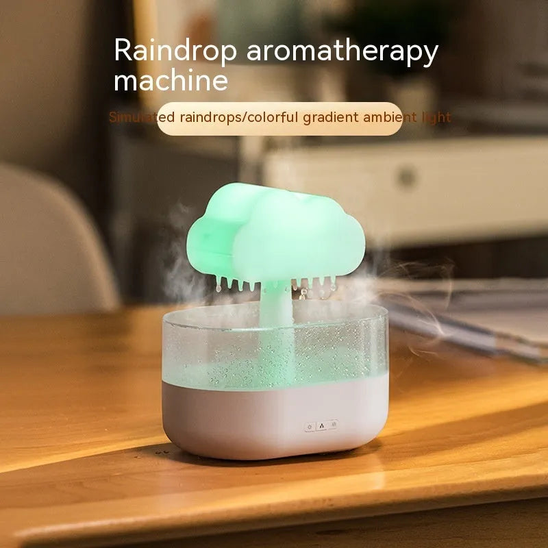 White cloud-shaped humidifier diffuser with multi-colour LED lights on a wooden surface.