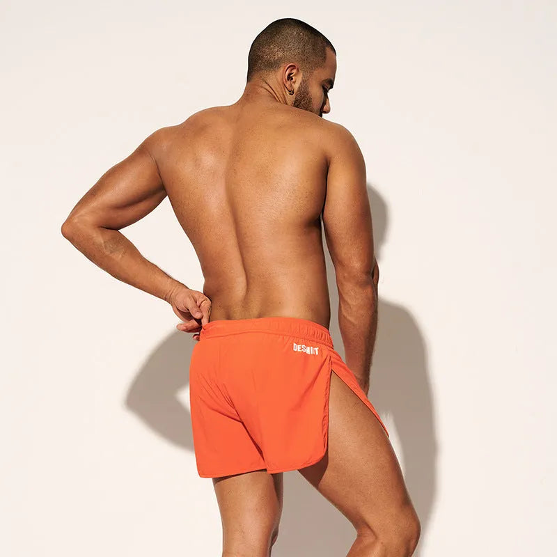 Men's loose beach surfing shorts in orange, fluorescent green, or black with elastic waistband and micro-elastic fabric