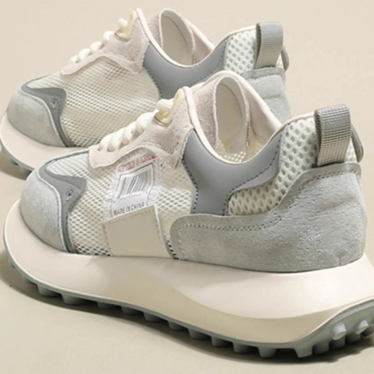 Women's grey and pink low-top retro sneaker with round toe and flat rubber sole.