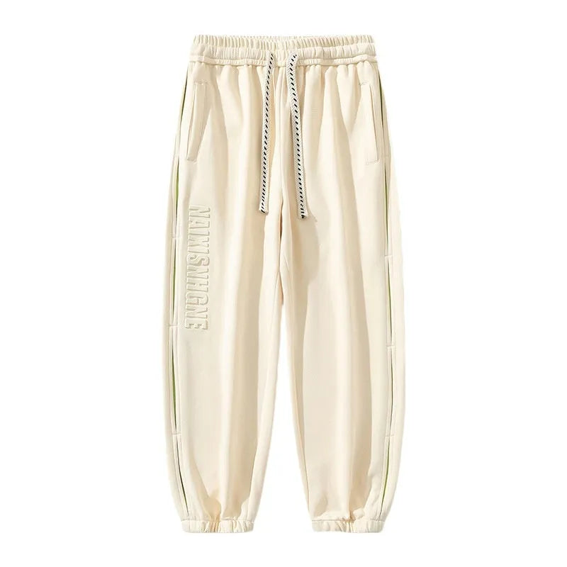 Men's ankle banded trousers in micro-elastic cotton with collage stitching, showing skinny leg and mid-waist fit.