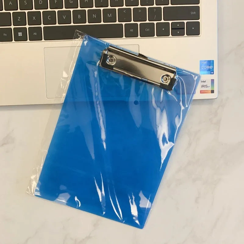 Clear A4 plate holder with metal clip and transparent writing pad in blue colour on a desk.