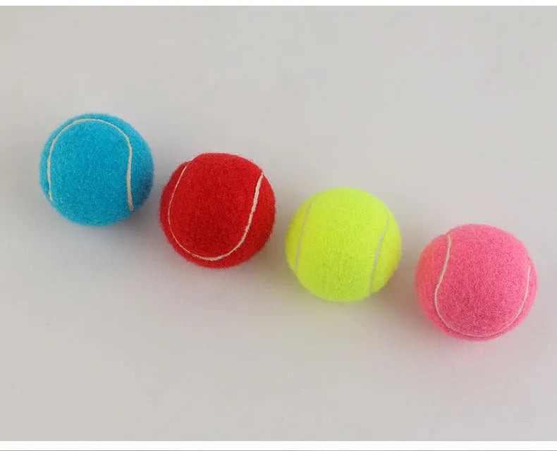 A 6.3cm pink rubber dog tennis ball sitting on grass.