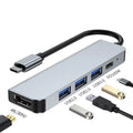 Compact silver USB-C expansion dock for laptops with multiple ports including HDMI and USB-A.