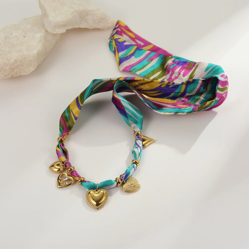 Geometric pendant on a stainless steel chain necklace next to a matching plated bracelet.