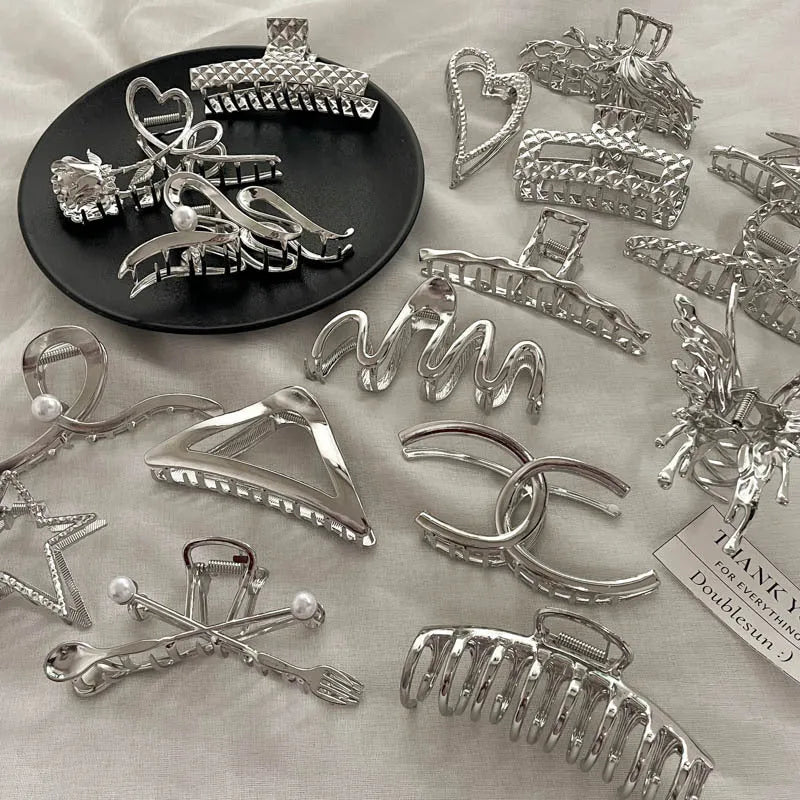 Assortment of silver metal hair claw barrettes in various shapes including waves, bows, and crosses.