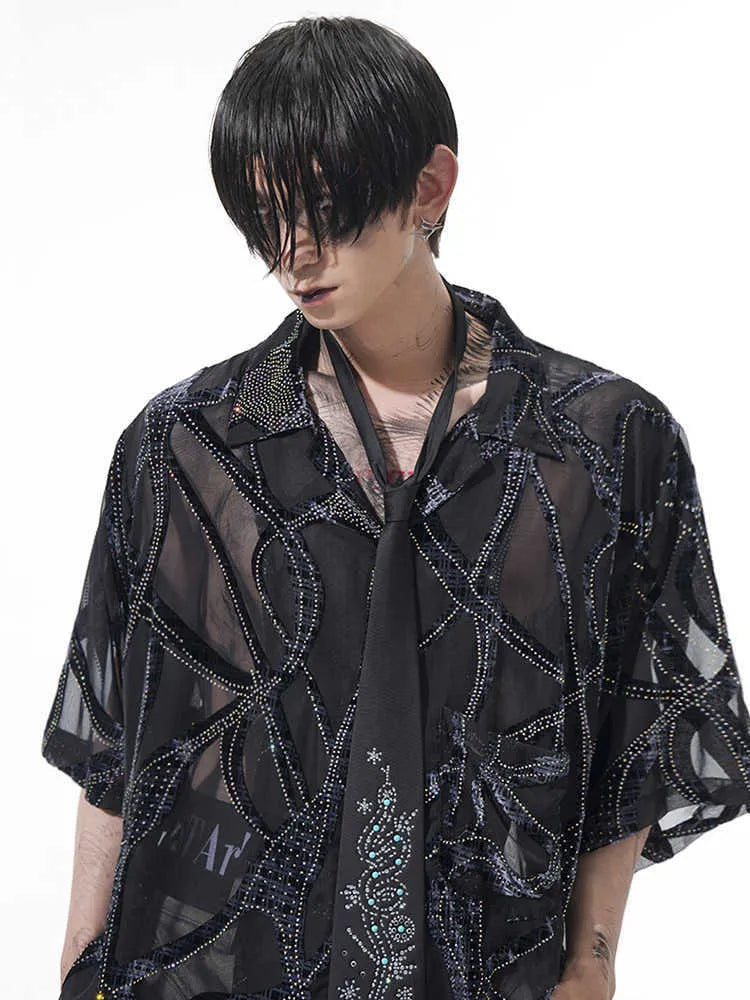 Man wearing a black translucent short-sleeved shirt with a snake pattern, featuring a lapel collar and loose fit.