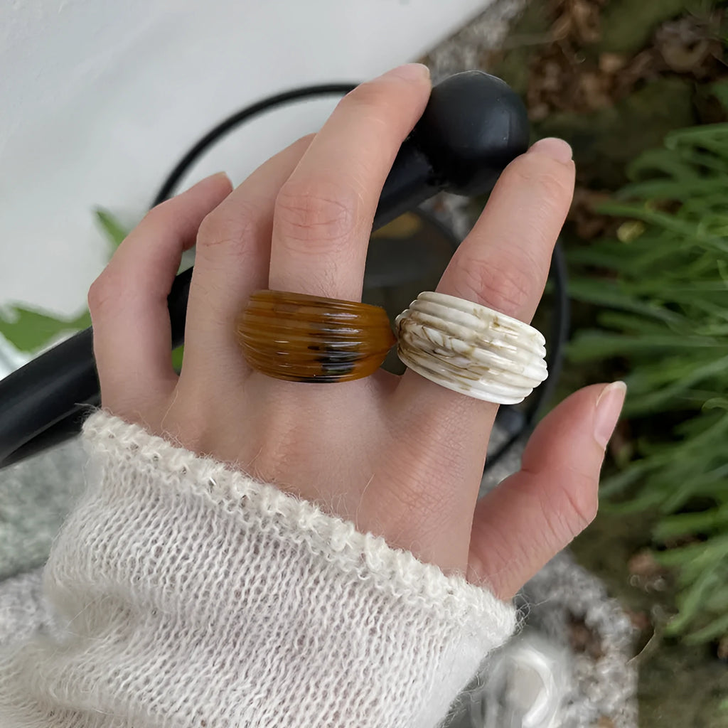 Geometric irregular resin wide ring in brown and white colour options on a hand.