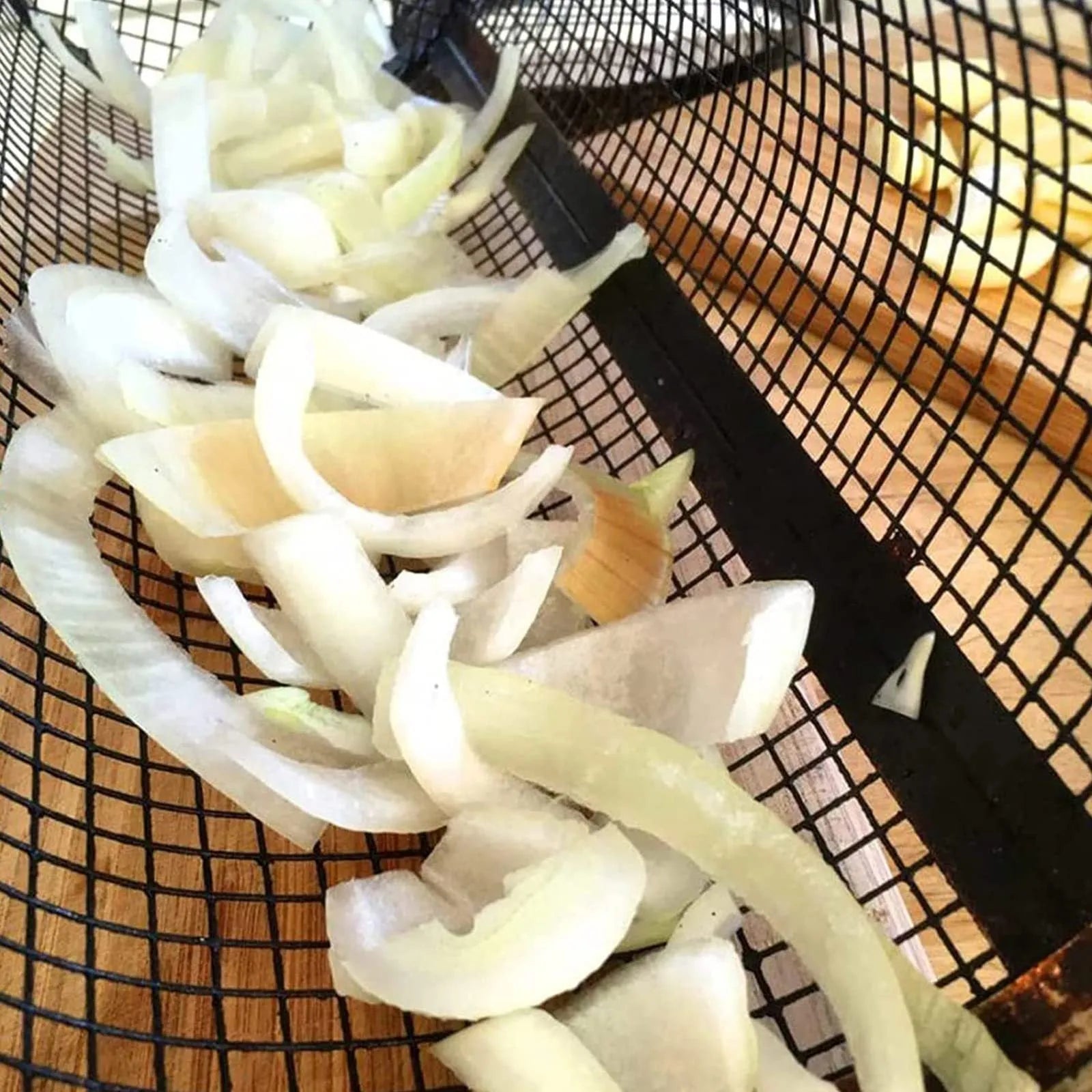 Stainless steel cylindrical rolling grill basket for BBQ with wire mesh, shown with vegetables inside.