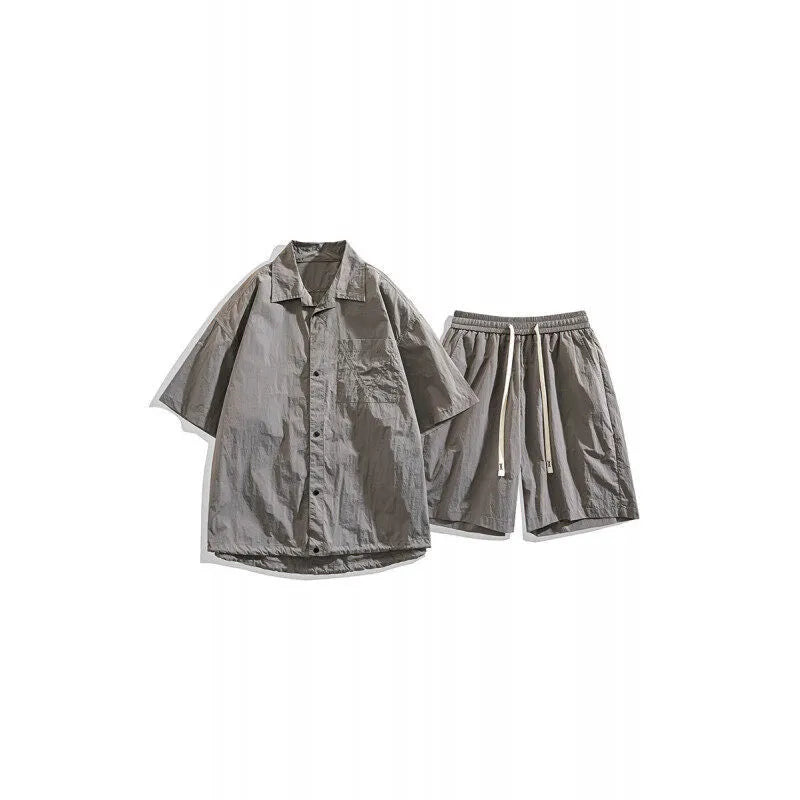 Man wearing a dark grey shirt and matching loose shorts from a men's casual two-piece set.