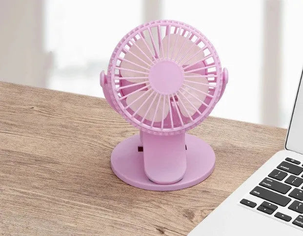 Small white clip-on personal desk fan with USB cable attached, shown clipped to a surface.
