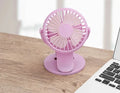 Small white clip-on personal desk fan with USB cable attached, shown clipped to a surface.