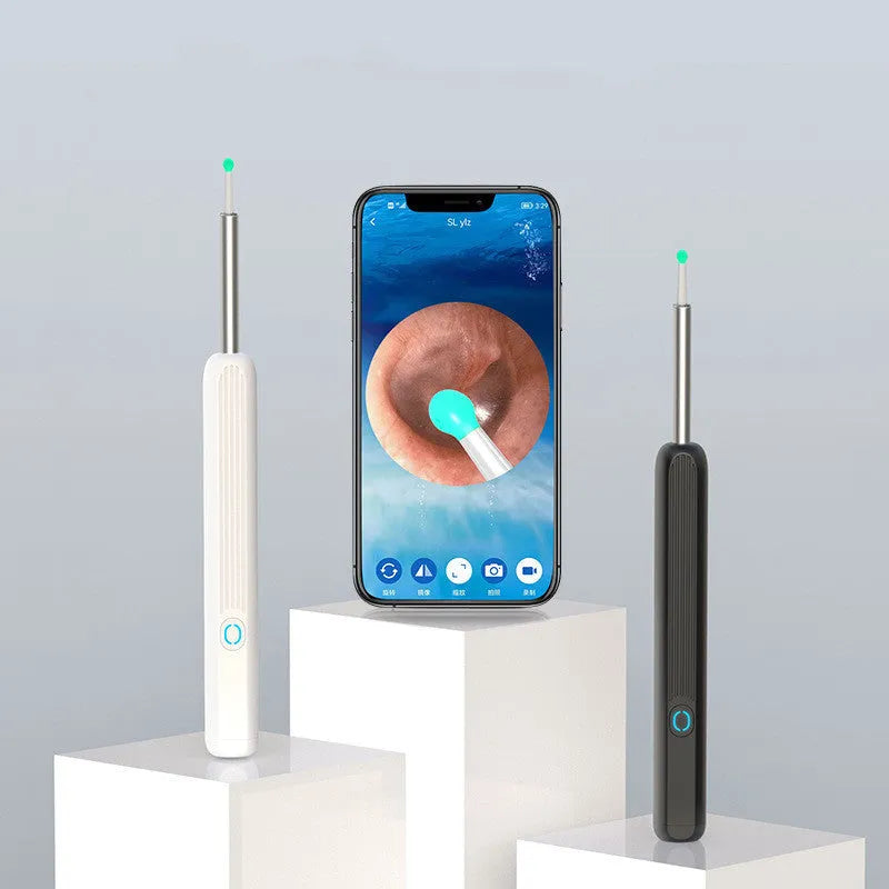 Black and white wireless otoscope ear cleaner with camera, LED light, and spoon heads on a table.