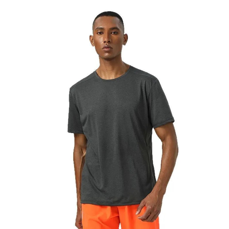 Man wearing a lightweight dark gray short sleeve sports top with reflective details on the sleeves.