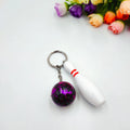 Mini bowling pin keychain pendant in four colours: dark red, blue, purple, green, showing PVC metal construction
