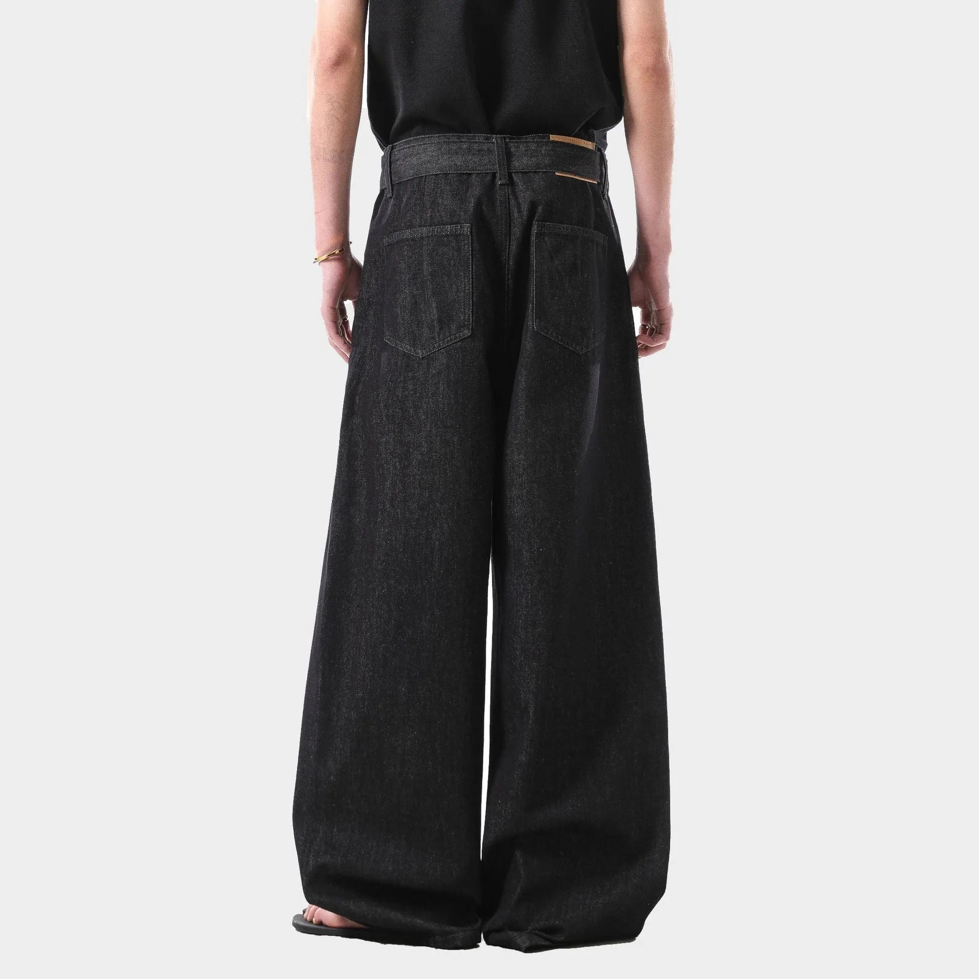 Black high-waist straight-leg jeans with a zip placket fly, made from cotton denim, shown in a casual setting.