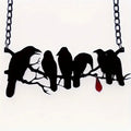 Black crow pendant necklace with cross chain on dark background