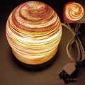 Modern simple style planet night light with USB cable on a wooden surface.