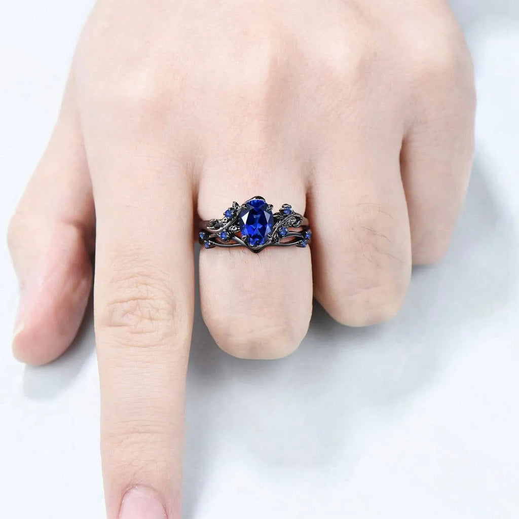 Gun black and navy blue rhinestone geometric couple ring for women on a plain background.
