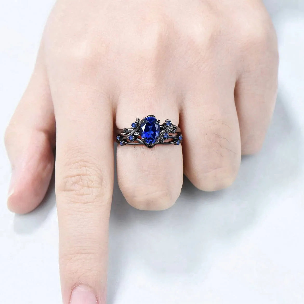 Gun black and navy blue rhinestone geometric couple ring for women on a plain background.