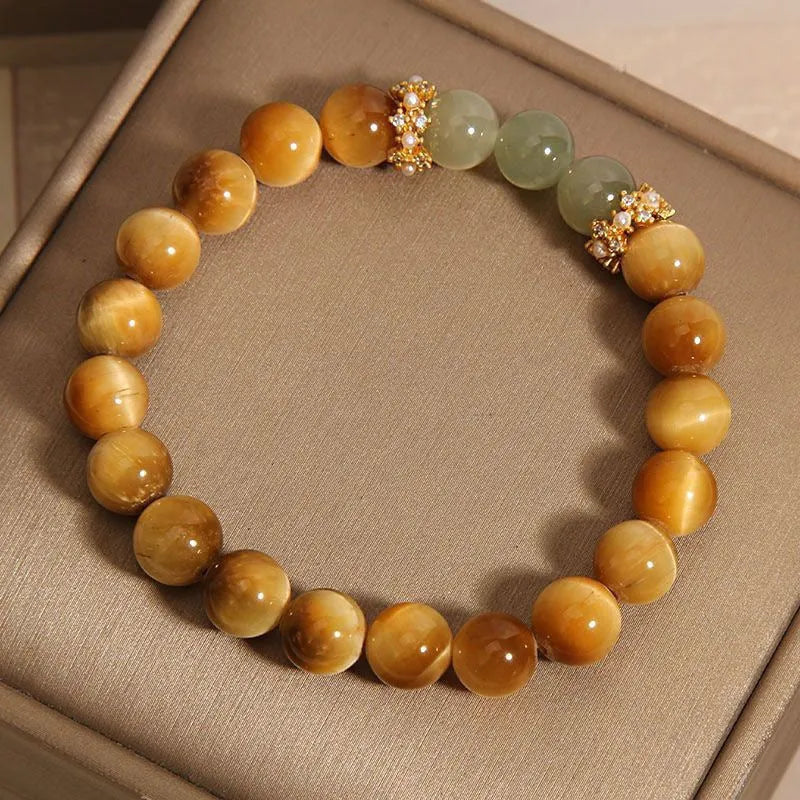 Natural yellow tiger's eye stone bead bracelet with gold gourd charm on a white background.