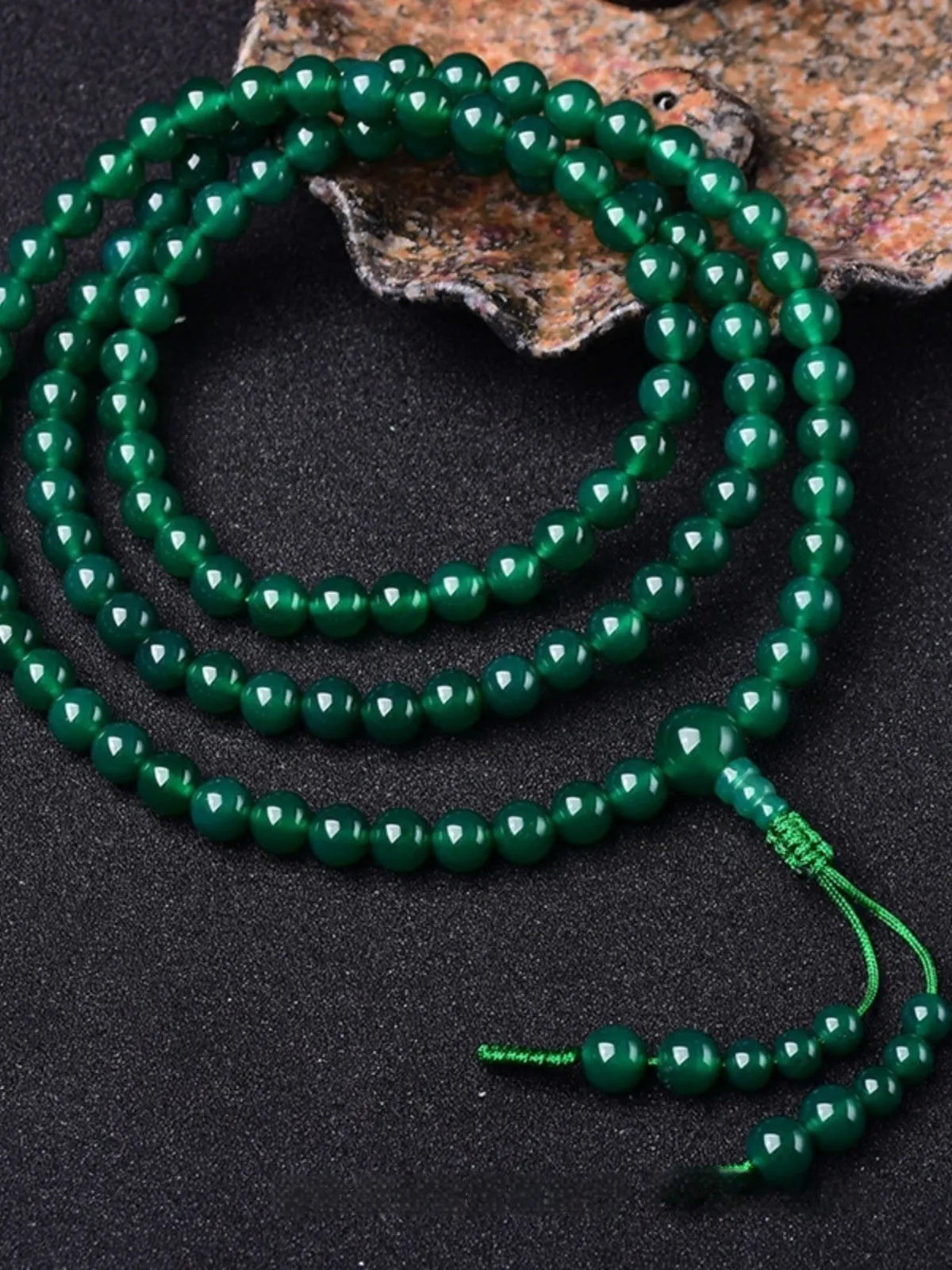 Green agate beaded bracelet with a multi-circle 108-bead thangka pendant on a wrist.