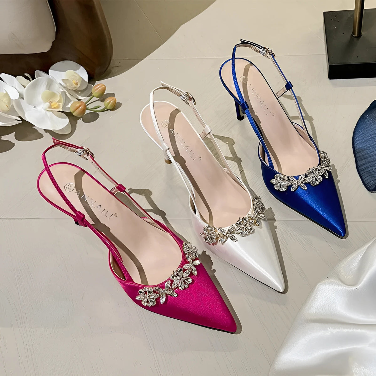 Women's satin stiletto high heels with rhinestone closed toe and buckle fastening in white, rose red, or blue